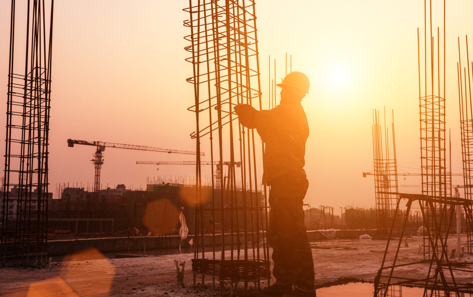 workerworkingwithconcreteironnearsunset